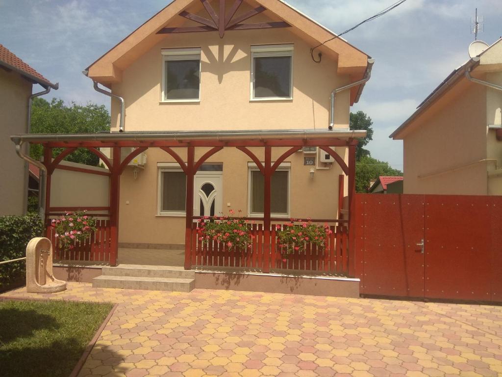 a house with a red fence and a red gate at Holiday Home Rose in Hajdúszoboszló