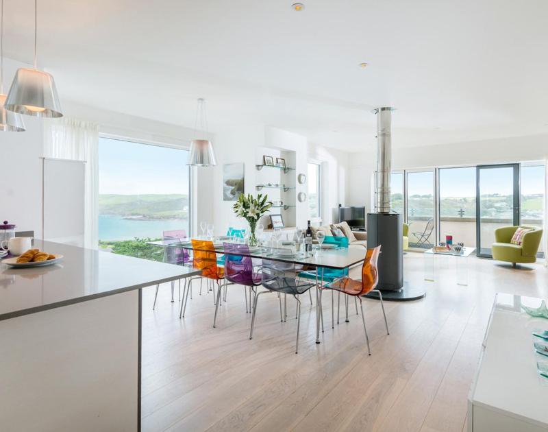 a kitchen with a glass dining table and chairs at Stepper Point in Polzeath