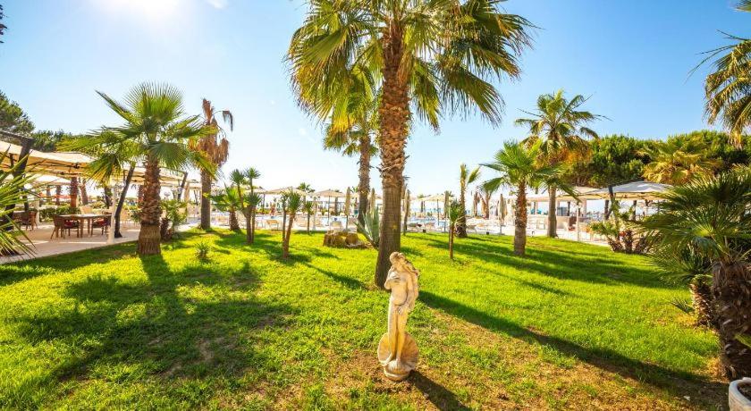 a woman standing in a park with palm trees at Skampini Qerret Apartments in Golem