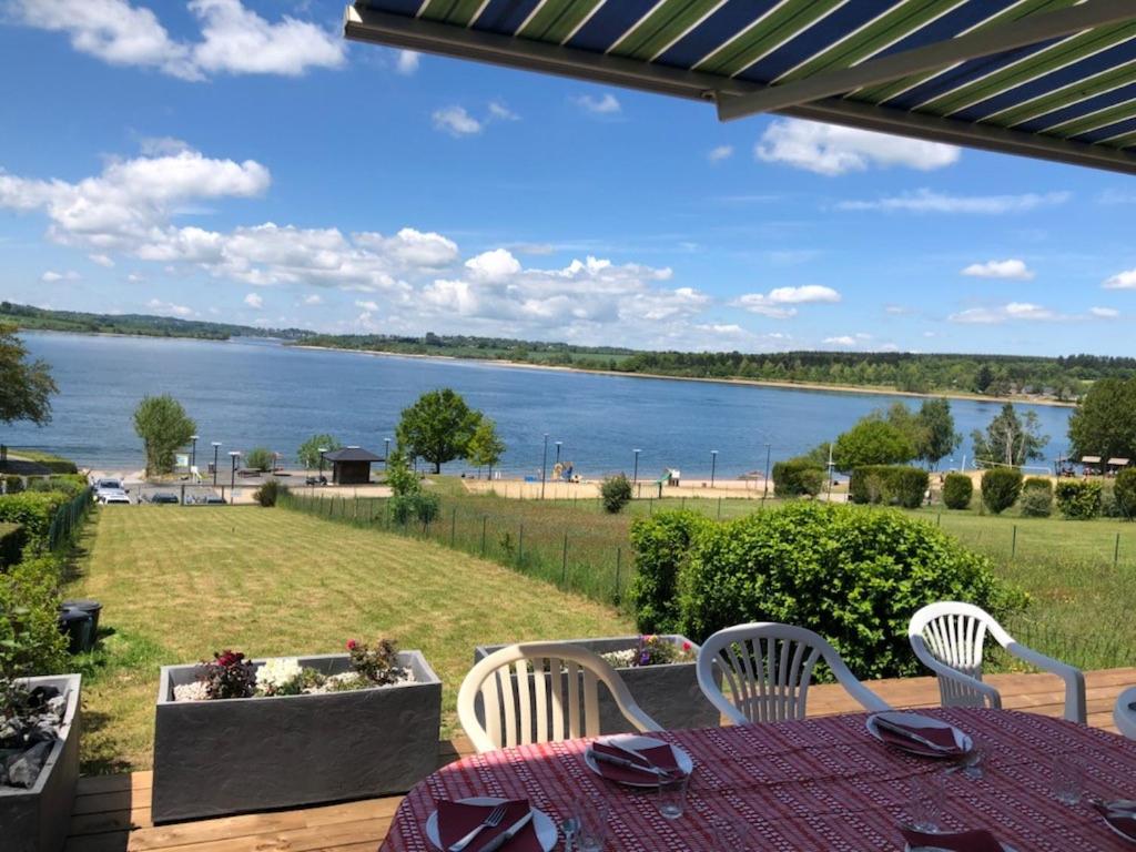a patio with a table and chairs and a view of a lake at Maison bord de Lac de Pareloup in Salles-Curan