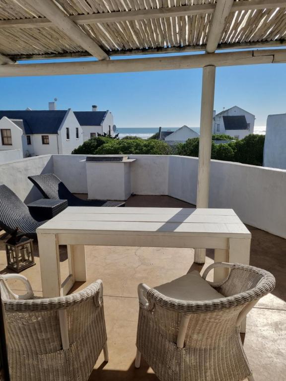 a table and chairs on a patio with a view of the ocean at Mosselbank Beach Retreat in Paternoster