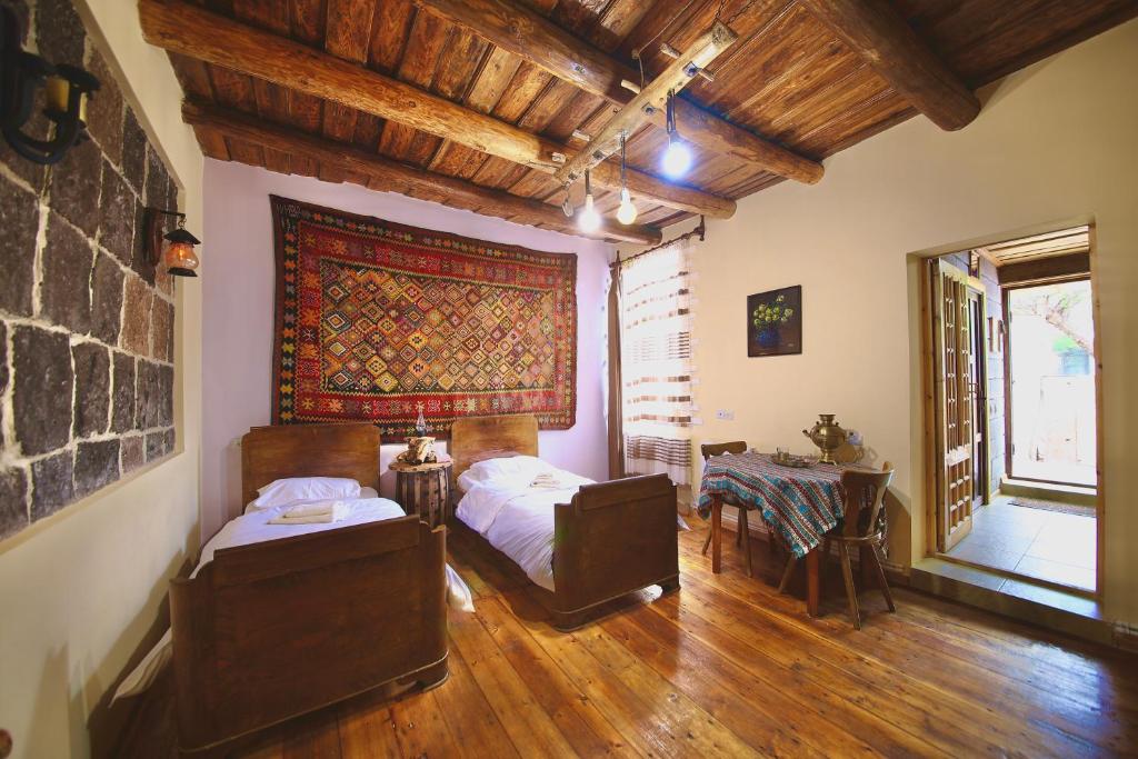 Zimmer mit 2 Betten, einem Tisch und einem Fenster in der Unterkunft Alashkert Guesthouse ,Ալաշկերտ Հյուրատուն in Gjumri