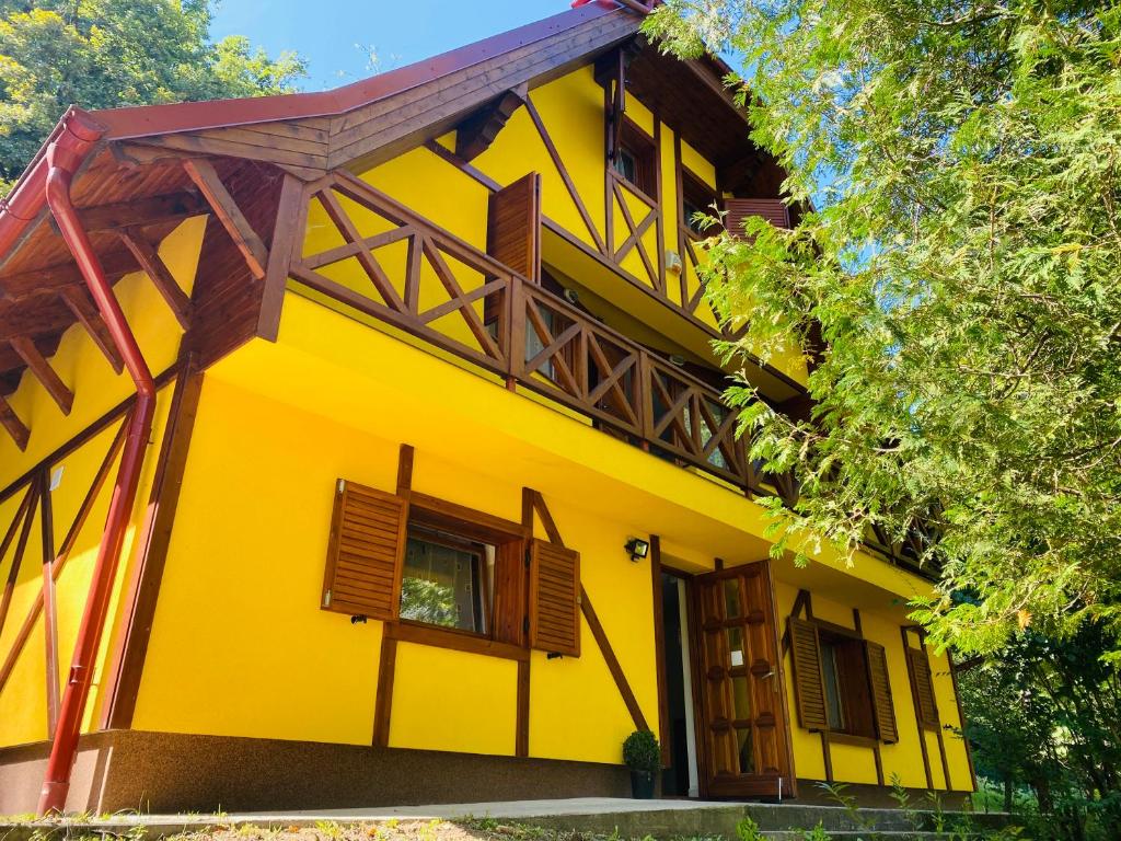 uma casa amarela com janelas de madeira e uma porta em Tavas Vendégház em Karancsalja