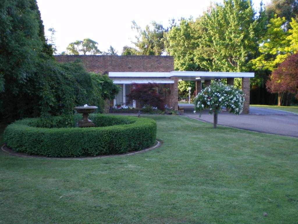 una casa con un patio verde con una fuente en Oxley Motel en Bowral