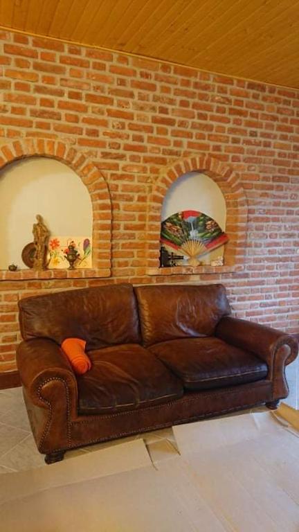 a brown leather couch in front of a brick wall at Majorka in Balatonfenyves