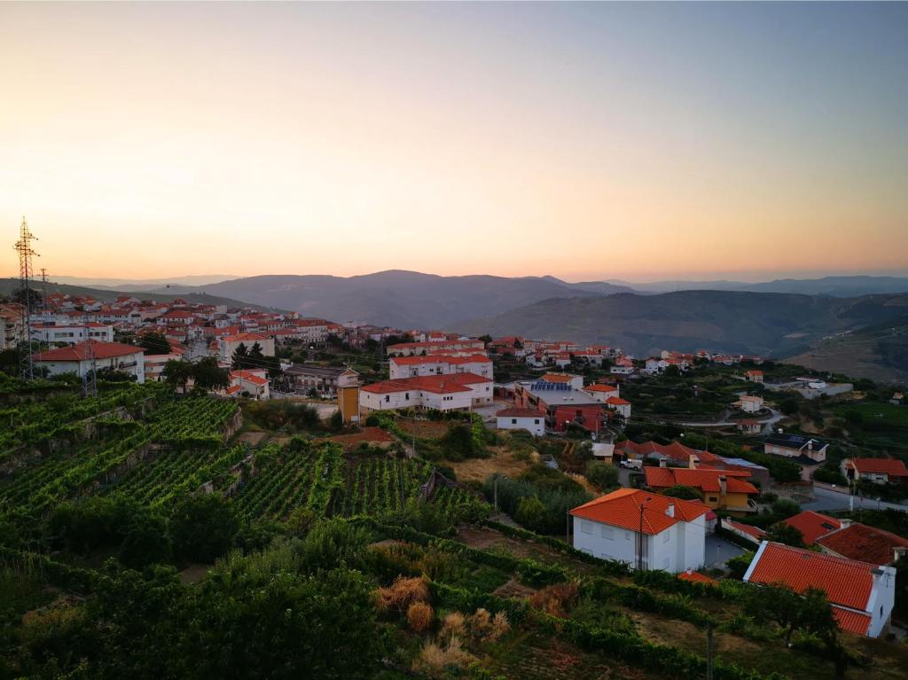 een stad op een heuvel met een wijngaard bij zonsondergang bij Casa da Quinta in Tabuaço