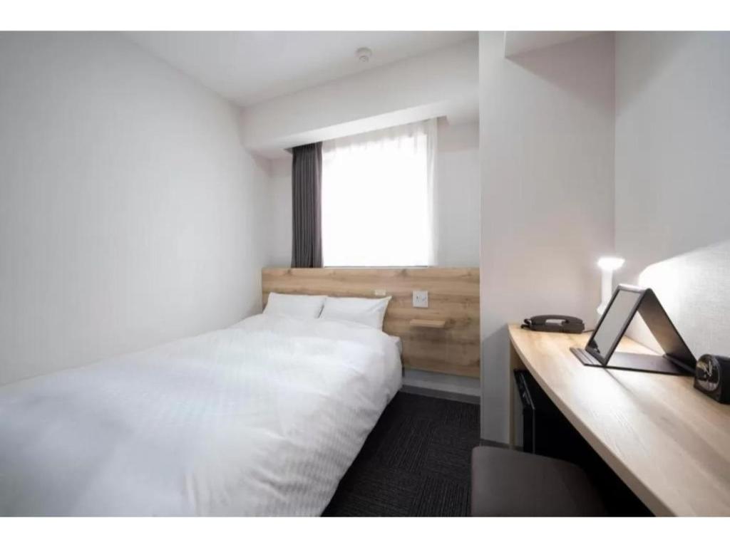 a bedroom with a bed and a desk with a laptop at R&B Hotel Nagoya Shinkansenguchi - Vacation STAY 40535v in Nagoya