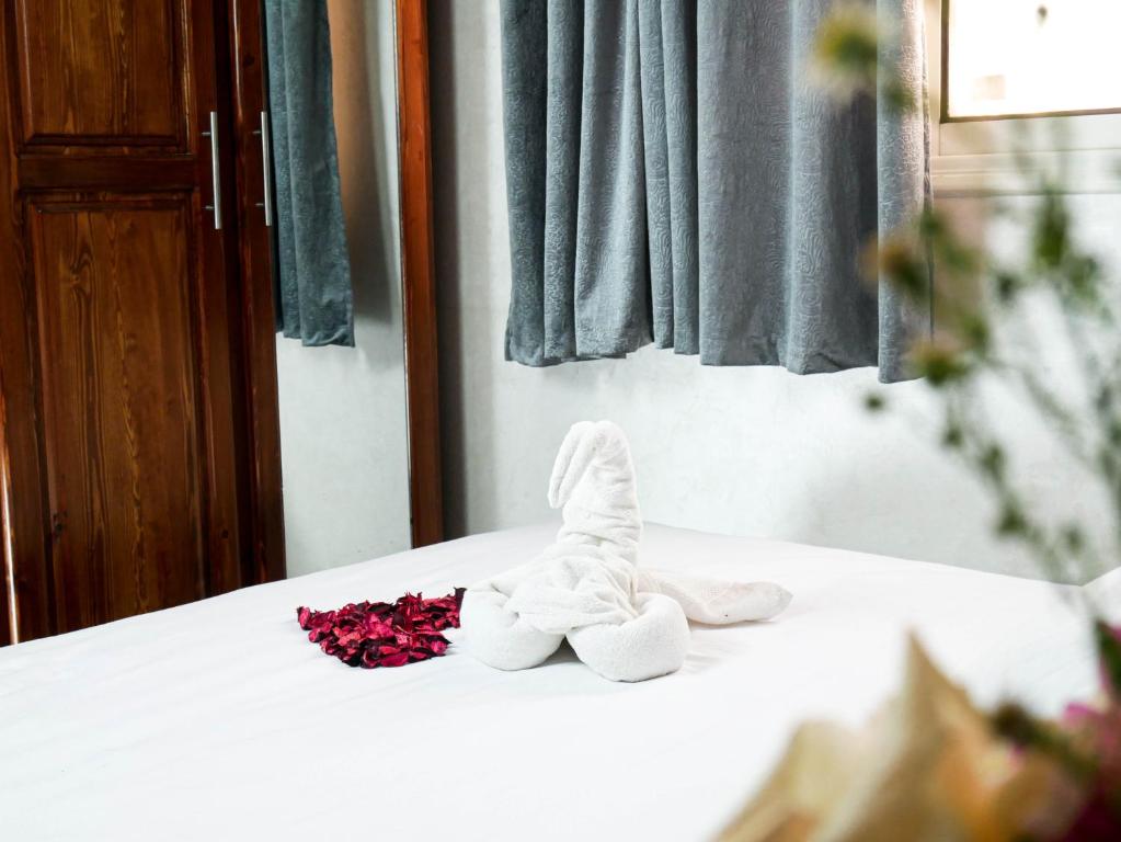 a pair of white shoes and flowers on a bed at Ayouz House Hotel in Dakhla