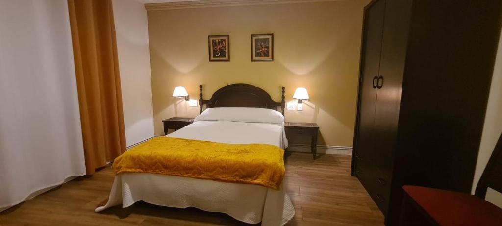 Un dormitorio con una cama con una manta amarilla. en La casa de la abuela en Narón