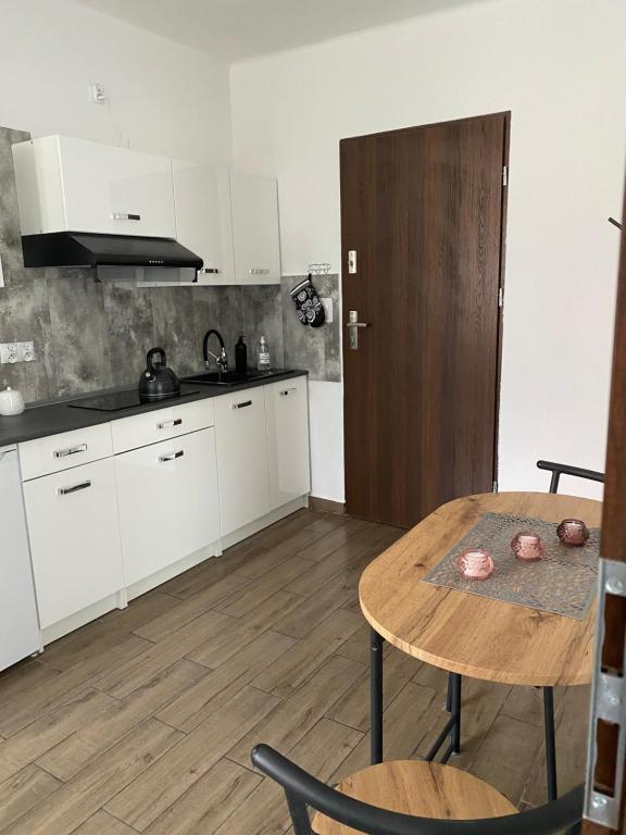 a kitchen with white cabinets and a wooden table at Apartamenty Otrytturystyka in Ustrzyki Dolne