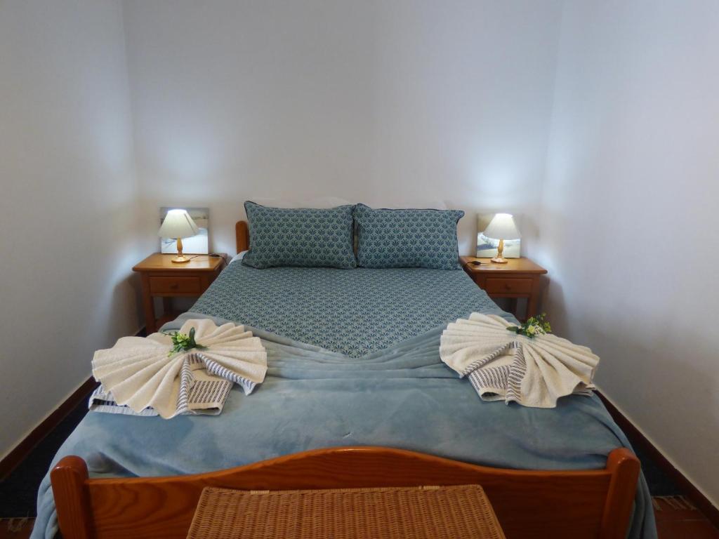 a bedroom with a bed with two lamps on both sides at Apartamento Rosa in Vila Nova de Milfontes