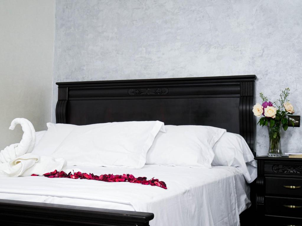 a white bed with a black headboard and a vase of flowers at Ayouz House Hotel in Dakhla