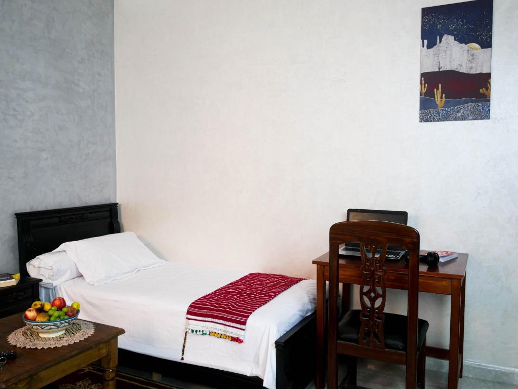 a bedroom with a bed and a table with a bowl of fruit at Ayouz House Hotel in Dakhla