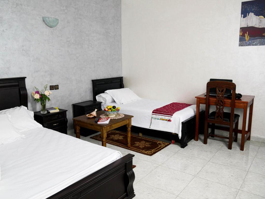 a bedroom with two beds and a table and a desk at Ayouz House Hotel in Dakhla