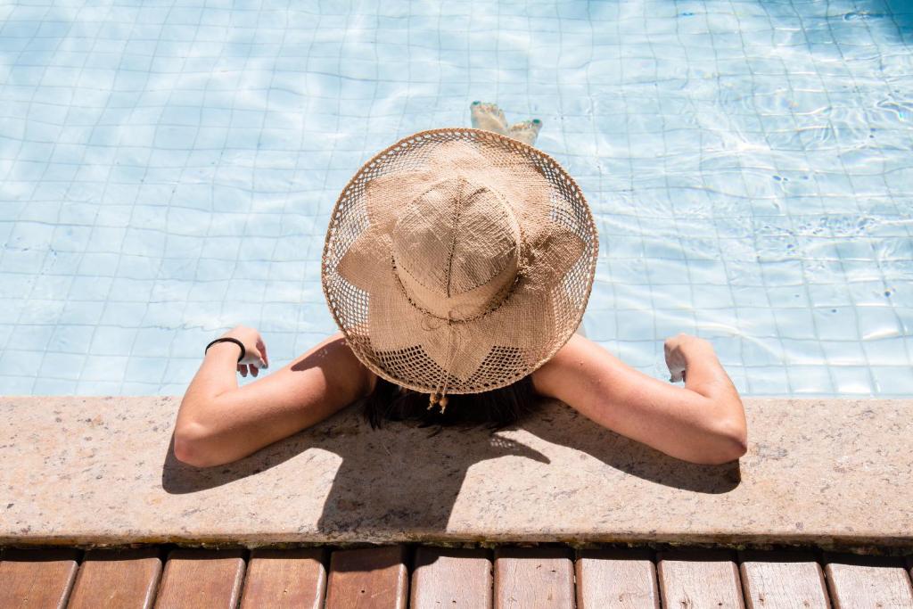 Pousada Aguas Claras في بوزيوس: امرأة ذات قبعة جالسة بجوار حمام السباحة