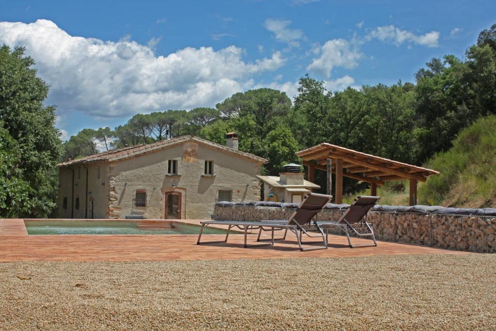 une terrasse avec 2 chaises et une maison dans l'établissement Casa Rural Masia Can50, à Vallgorguina