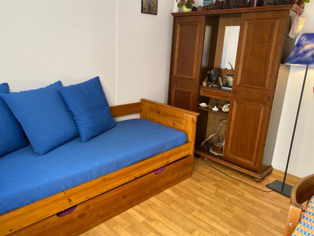 un sofá con almohadas azules sentado en una habitación en Soustons plage Maison terrasse 2 pers et 1 enfant Les villas du lac Tennis mini golf en Soustons