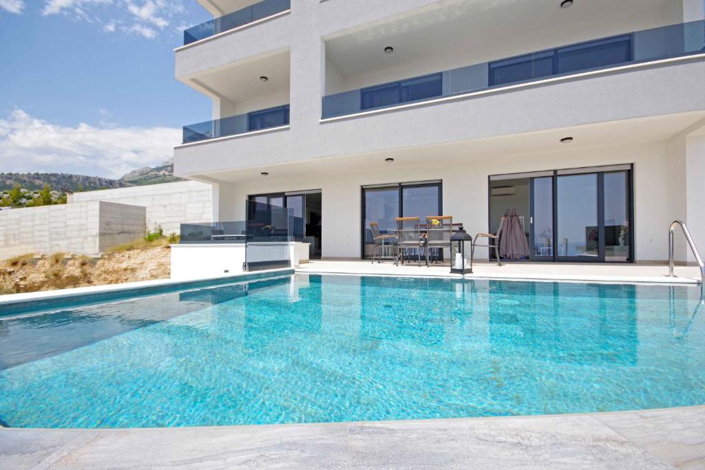 a villa with a swimming pool and a house at Sunset Apartments in Makarska