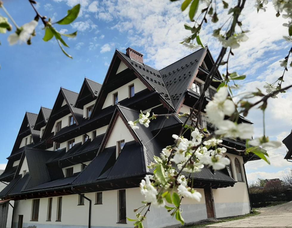 a building with a black roof with white flowers at Górski Ośrodek Wczasowy Kościelec in Czarna Góra