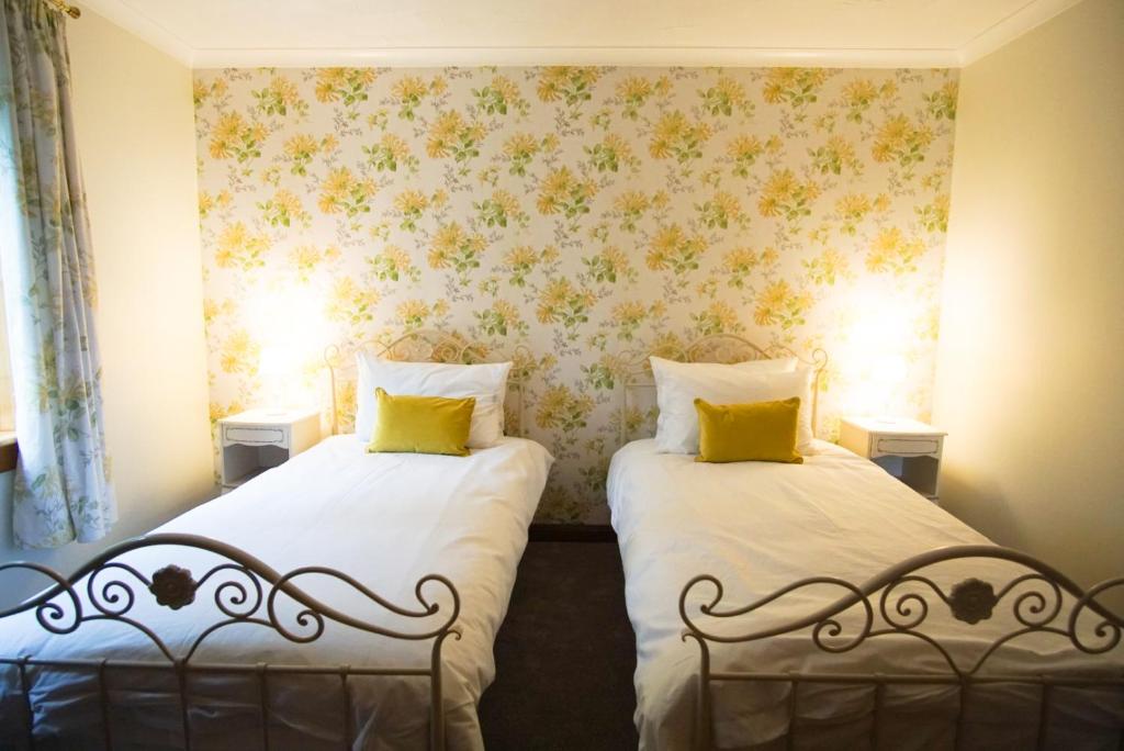 two beds in a room with floral wallpaper at Remuera, North Tolsta in North Tolsta