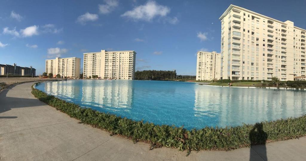 una gran piscina de agua frente a los edificios en Departamento Laguna Bahía Algarrobo, en Algarrobo