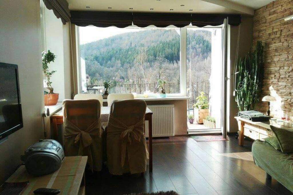 a living room with a table and a large window at Apartament rodzinny 2 pokojowy. Widok na Snieżke. in Karpacz