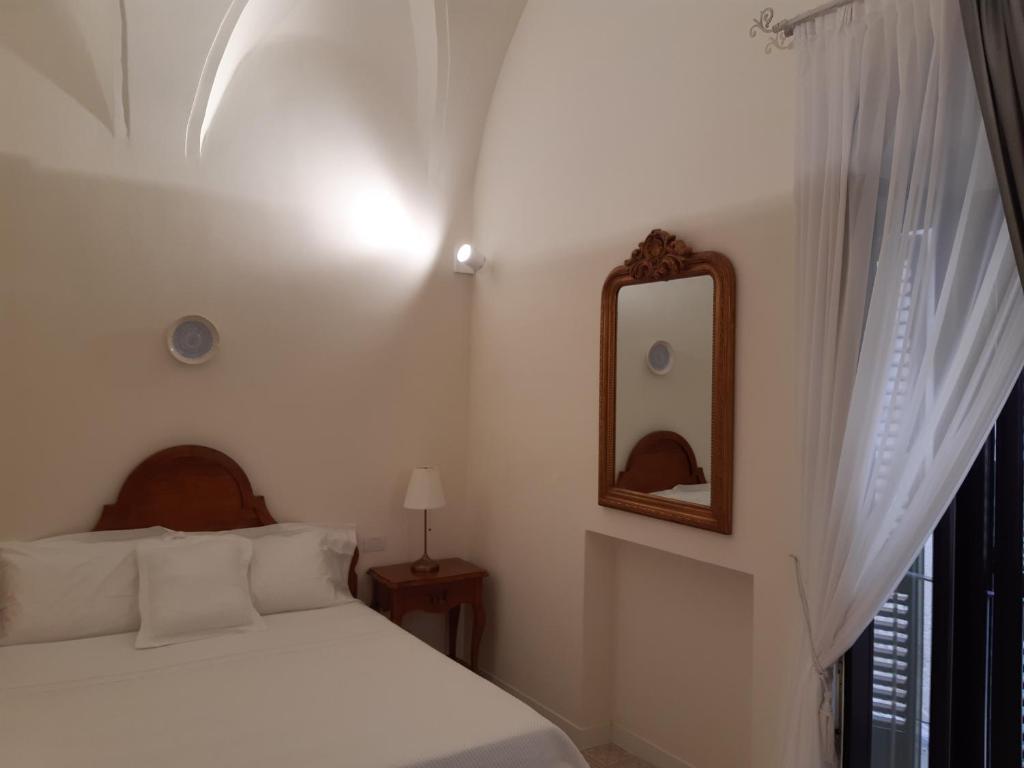 a white bedroom with a bed and a mirror at Estlevante B&B in Vieste