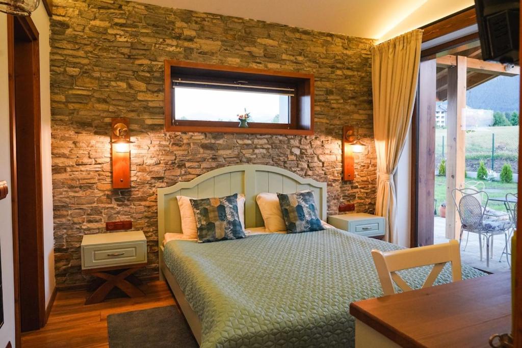 a bedroom with a bed and a stone wall at Mountain villa Aleksia- with JACUZZI in Razlog