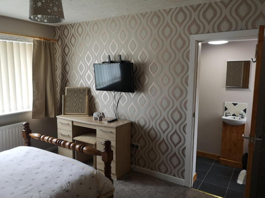 - une chambre avec un lit et un bureau avec une télévision dans l'établissement En-suite Bedroom in a quiet bungalow, à Porthmadog