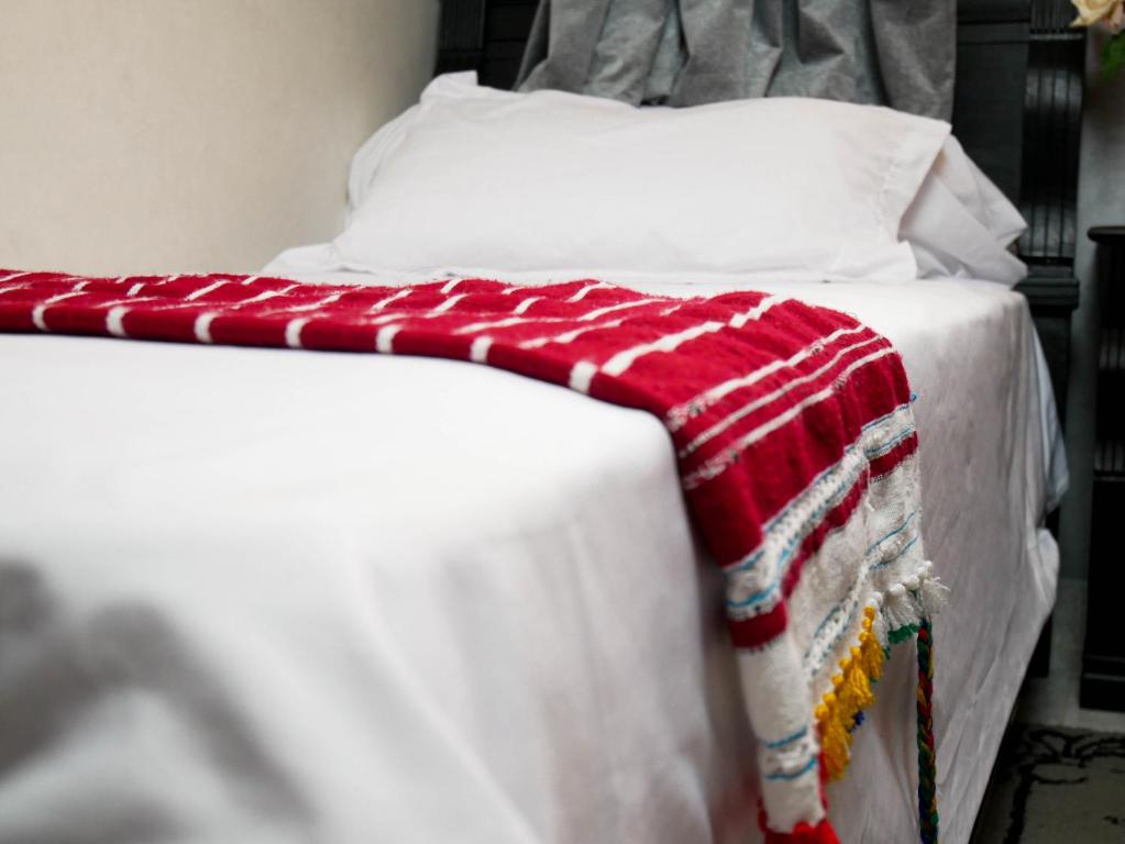 a bed with a red and white blanket on it at Ayouz House Hotel in Dakhla