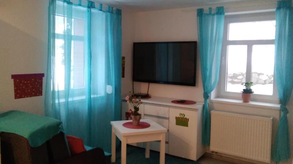 a living room with blue curtains and a television at Komfortowe noclegi w Villi blisko natury in Karpacz