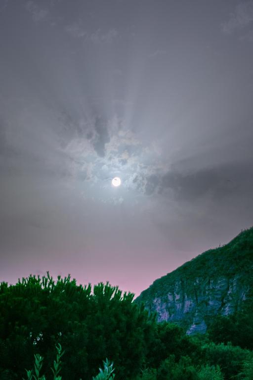 a moonrise over a mountain with trees in the foreground at Hotel Villa Rita in Ischia