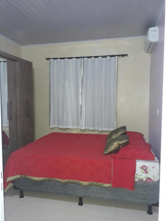 1 dormitorio con cama roja y ventana en Casa da Vila de São Jorge en Alto Paraíso de Goiás