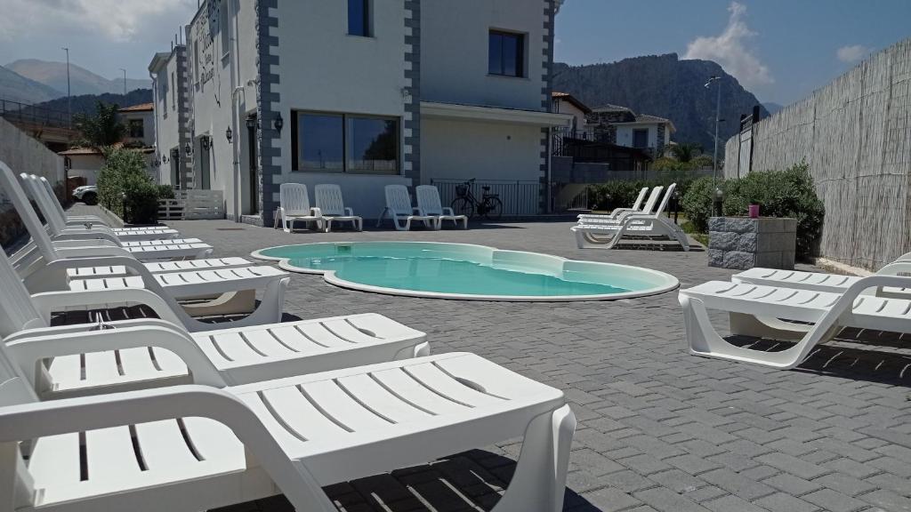 un gruppo di sedie a sdraio bianche e una piscina di Sicily Rooms Appartamenti a Carini
