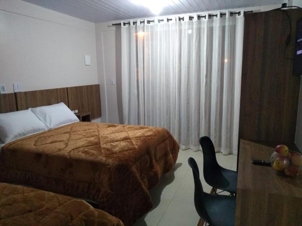 a hotel room with two beds and a table and chairs at Hospedagem Alternativa - Ana Paula in São Joaquim