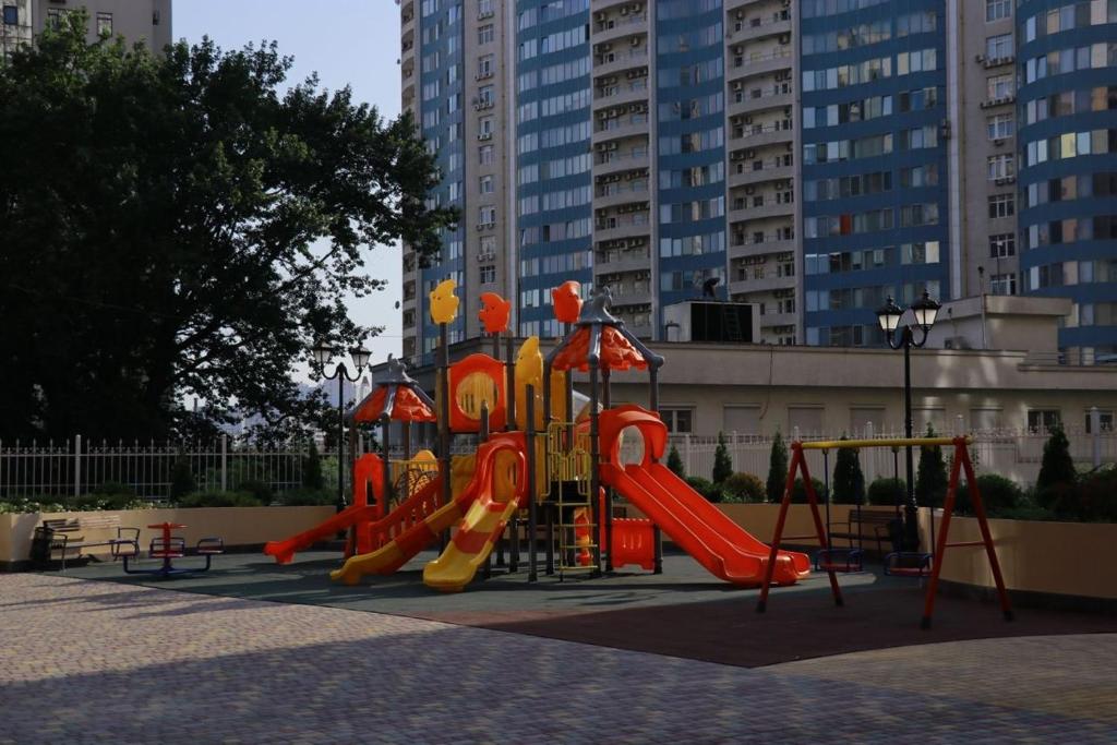 een speeltuin met een glijbaan in een park met hoge gebouwen bij Сдам квартиру в 51 жемчужине in Odessa