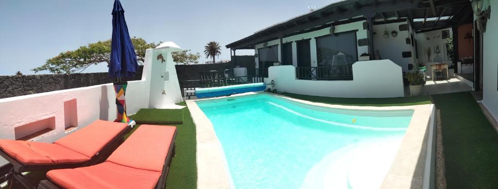 una piscina con 2 sillas y una casa en Aptos con piscina clima El Flamboyán 1, en Teseguite