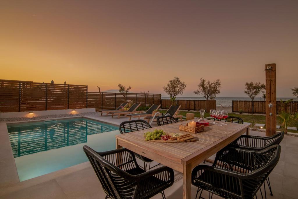 uma mesa de jantar e cadeiras ao lado de uma piscina em Alas Suites em Alykes