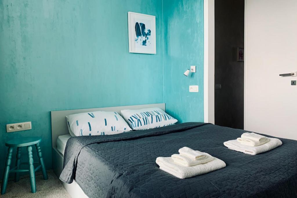 a blue bedroom with a bed with towels on it at Cozy Apartment - CityCentre - FreeParking - SelfCheck-in in Liptovský Mikuláš