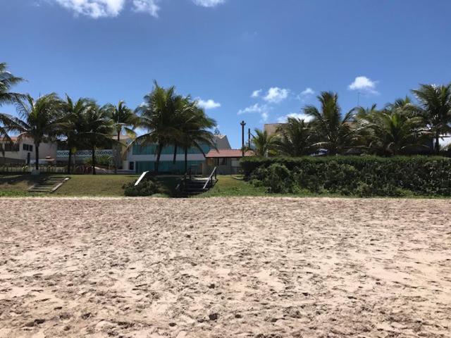 una spiaggia sabbiosa con palme sullo sfondo di Casa em condomínio à beira mar de Porto de Galinhas a Ipojuca