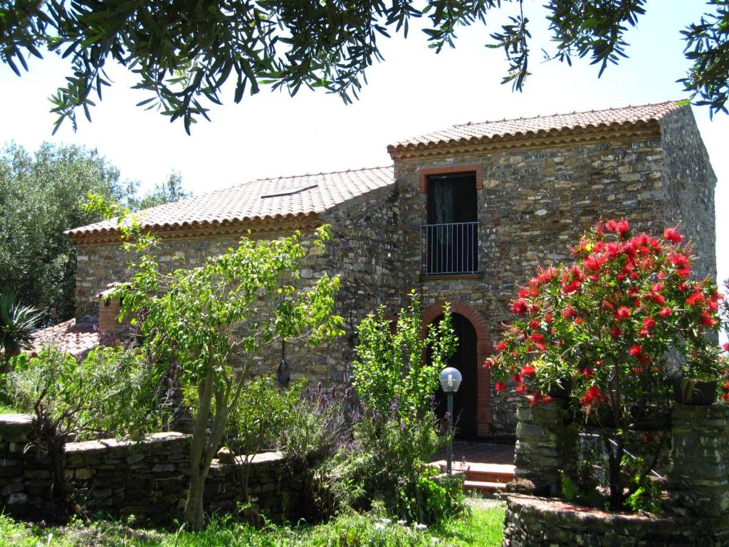 a stone house with a window and red flowers at Agriturismo La Casa Vecchia in Ascea