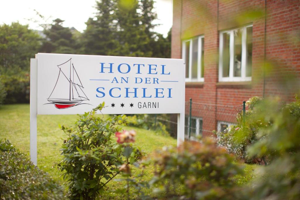 um sinal que lê hotel e der shuttle em frente a uma casa em Hotel an der Schlei Garni em Fahrdorf
