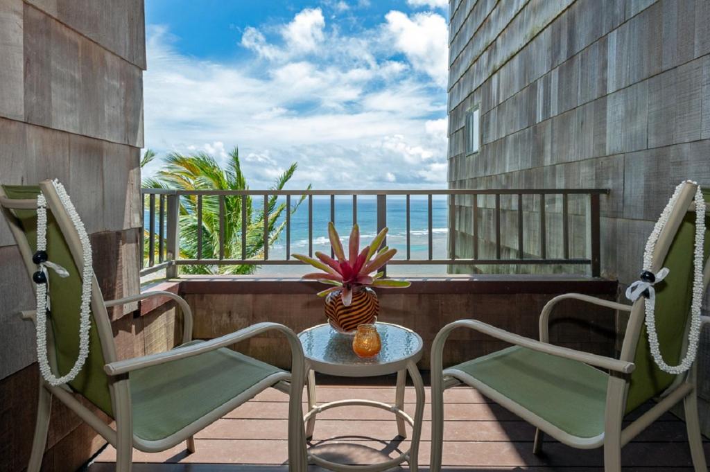 a balcony with chairs and a table with a vase on it at Sealodge G8 in Princeville