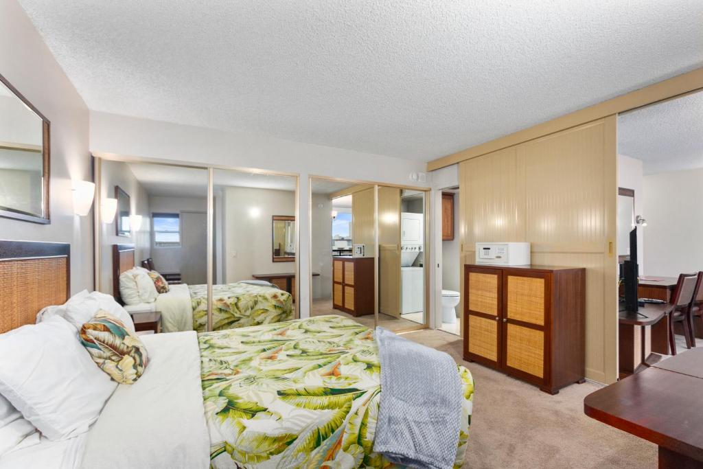 ホノルルにあるワイキキ ビーチ コンドミニアムズのベッドとデスクが備わるホテルルームです。