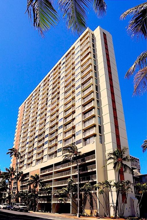 Un gran edificio con palmeras delante. en Waikiki Beach Condominiums, en Honolulu