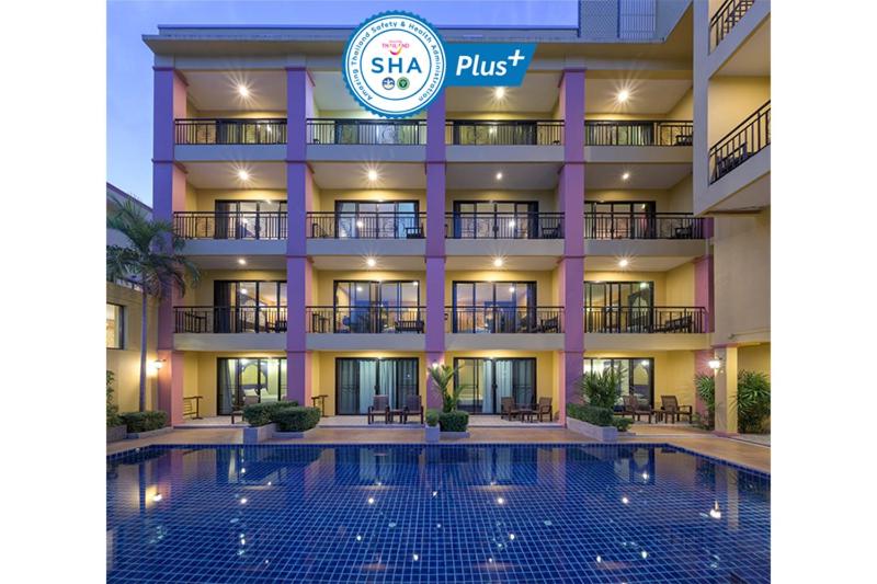 a hotel with a swimming pool in front of a building at Anchanlina Hotel - SHA Plus in Chalong 