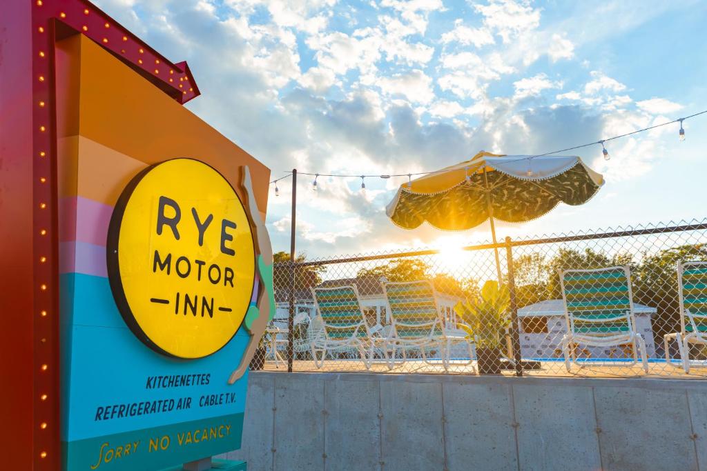 una señal para una posada rave motorinn junto a una valla en RYE MOTOR INN - An Adults Only Hotel, en Rye