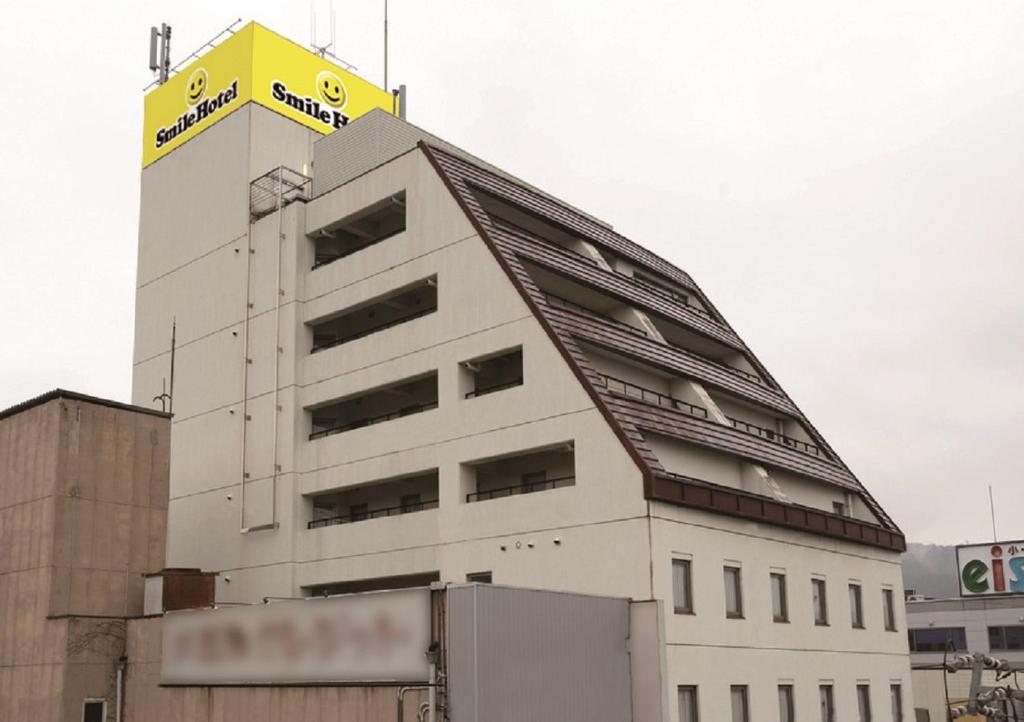 un edificio blanco con un letrero amarillo encima en Smile Hotel Nabari, en Nabari