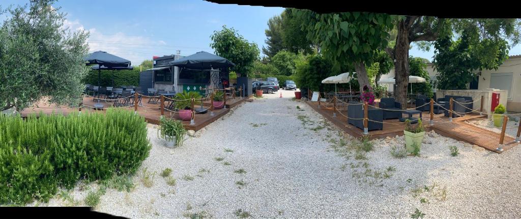 a garden with potted plants on a gravel road at Hôtel des Moulins in Allauch