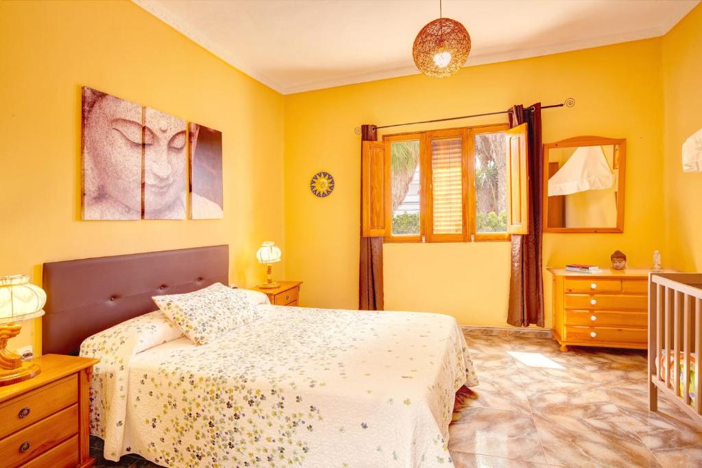 1 dormitorio con paredes amarillas, 1 cama y 1 cuna en Casa Eli, en Sardina